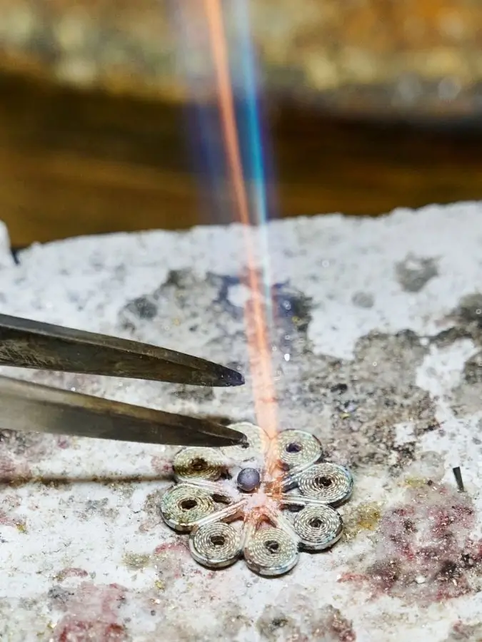 Zange und Schmuckstück auf Tisch während Goldschmiede-Arbeit