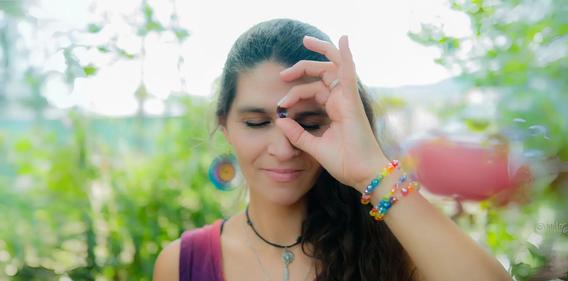 Martina im Garten ihrer Energetiker-Praxis in Graz Seiersberg. Sie hat die Augen geschlossen und hält einen glänzenden Edelstein vor ihr drittes Auge unter ihrer Stirn.