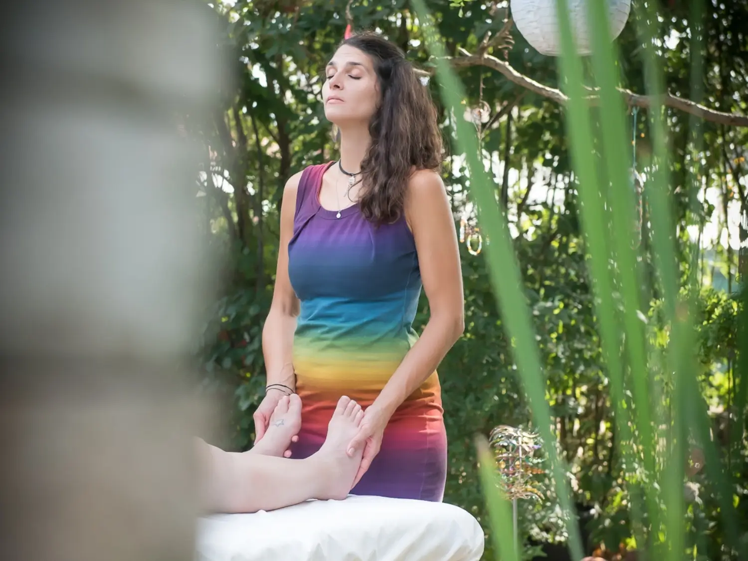 Martina hält die Füße einer Kundin während sie beim Reiki im Garten ihrer Praxis in Graz Seiersberg die Energie fließen lässt. Sie scheint sehr konzentriert und hält die Augen dabei geschlossen.